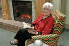 Resident reading a book in front of the fireplace